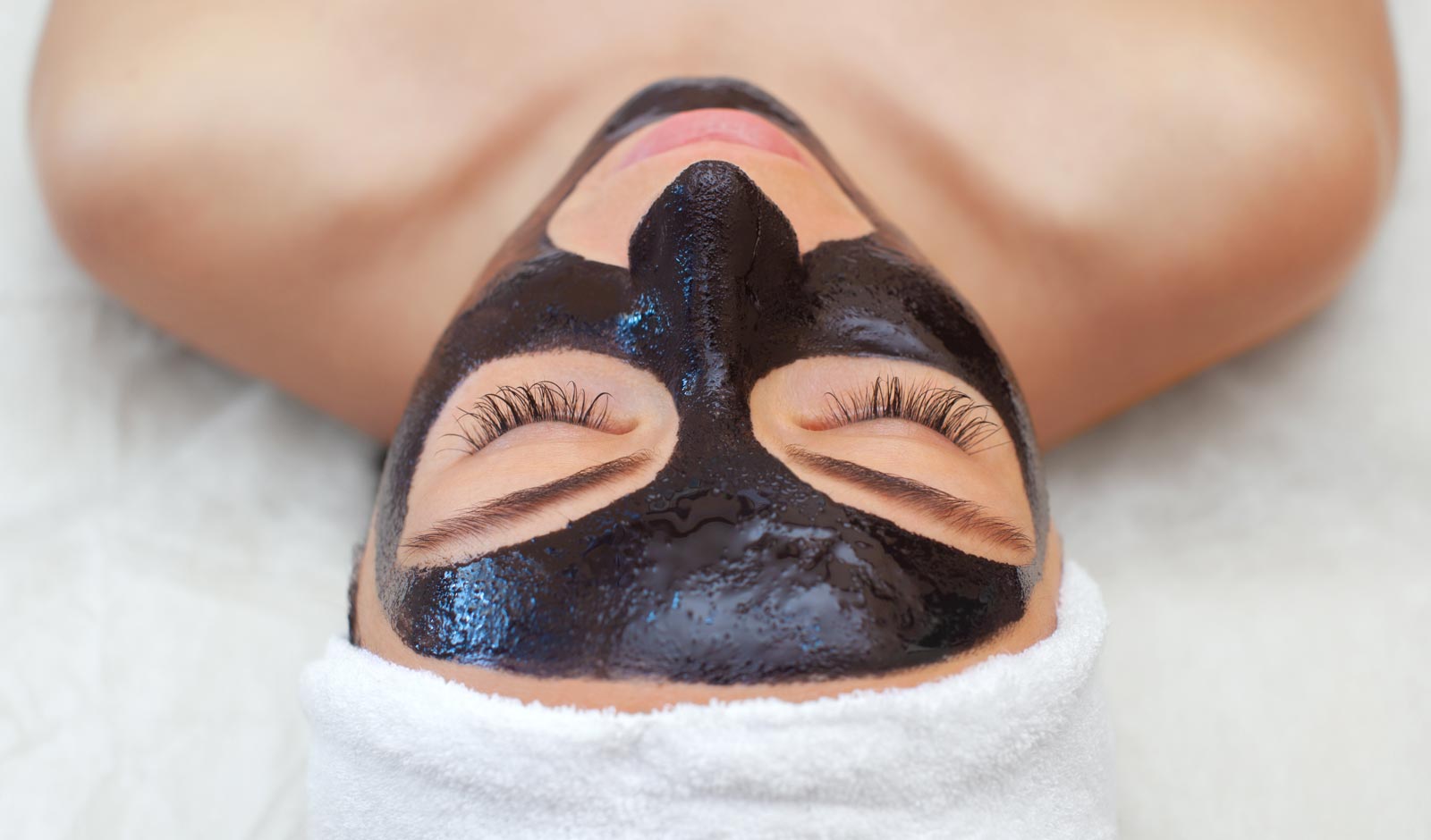 Person receiving a carbon facial treatment with a black mask.