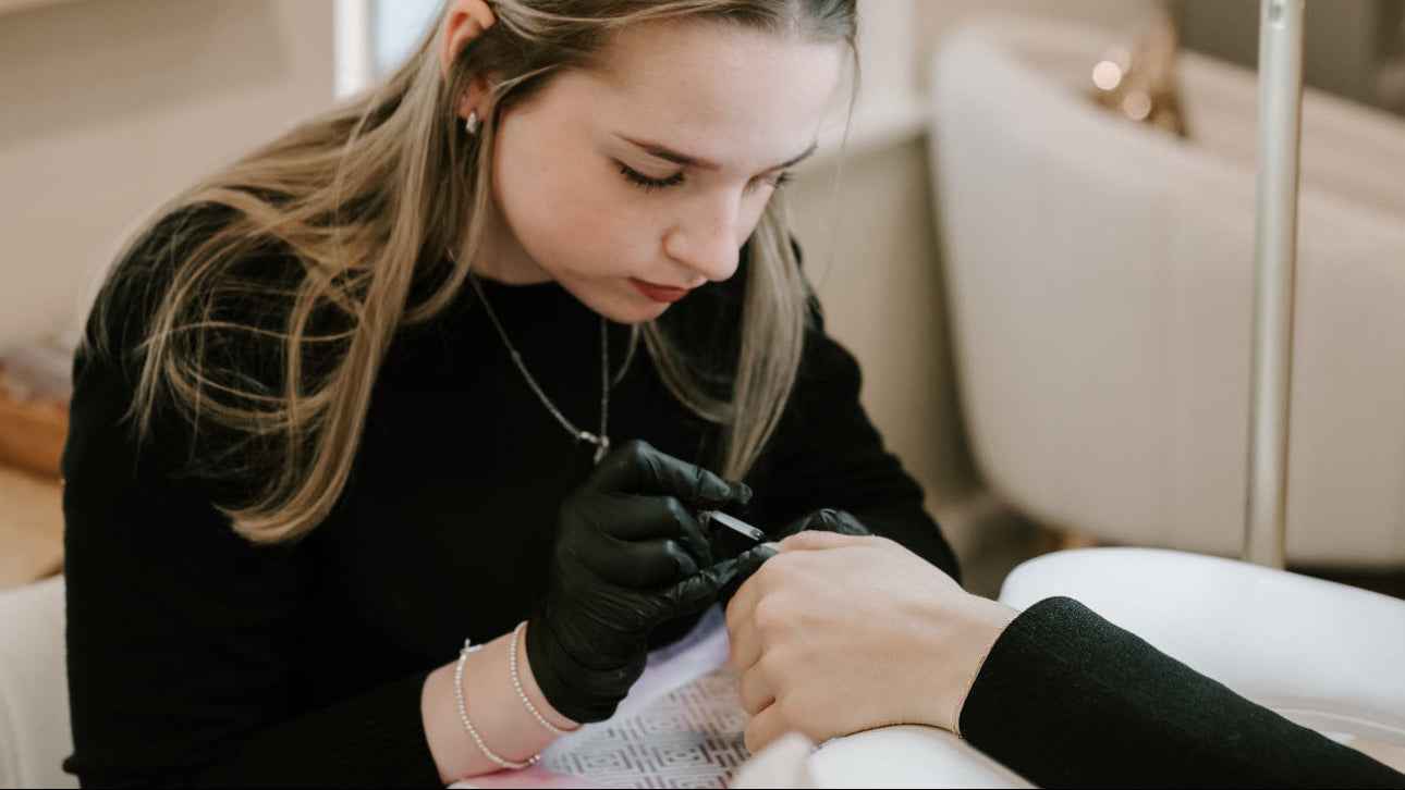 Nail technician applying nail polish to a client in a salon setting.